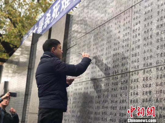 10日晨，下著小雨。南京大屠殺幸存者、死難者遺屬、學(xué)生們依次描寫名字，祭悼南京大屠殺遇難同胞。淡淡的墨汁摻著雨水，滲入了刻在紀(jì)念館灰色厚重石壁上的黑色名字中?！≈鞎苑f 攝